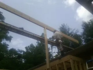 Carpenter setting a ridge beam over a new addition frame — Ice Dam Removal by Roofing Brothers in New Troy