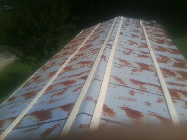 Rusted metal roof panels with new wood purlins before replacement — Storm Damage Roof Repair in New Troy by Roofing Brothers