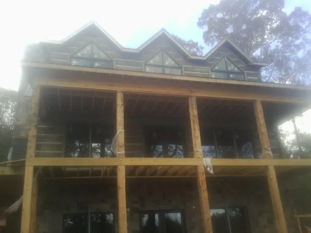Dormers and porch framing on a large log home under construction — Roof Coating work by our crew in New Troy