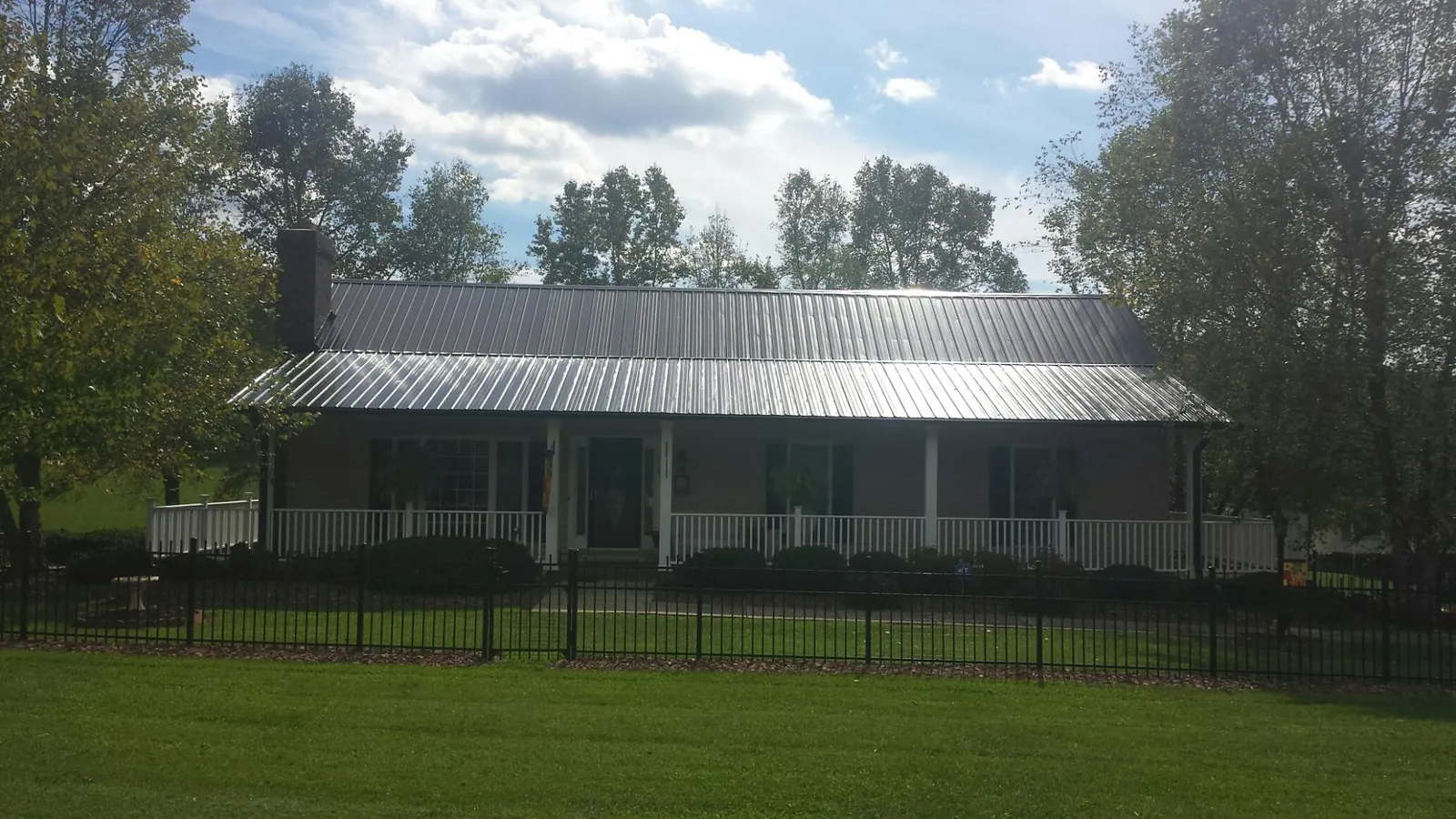 Gray metal roof on a brick ranch with a full width front porch — Gutter Guard Installation work by our crew in New Troy