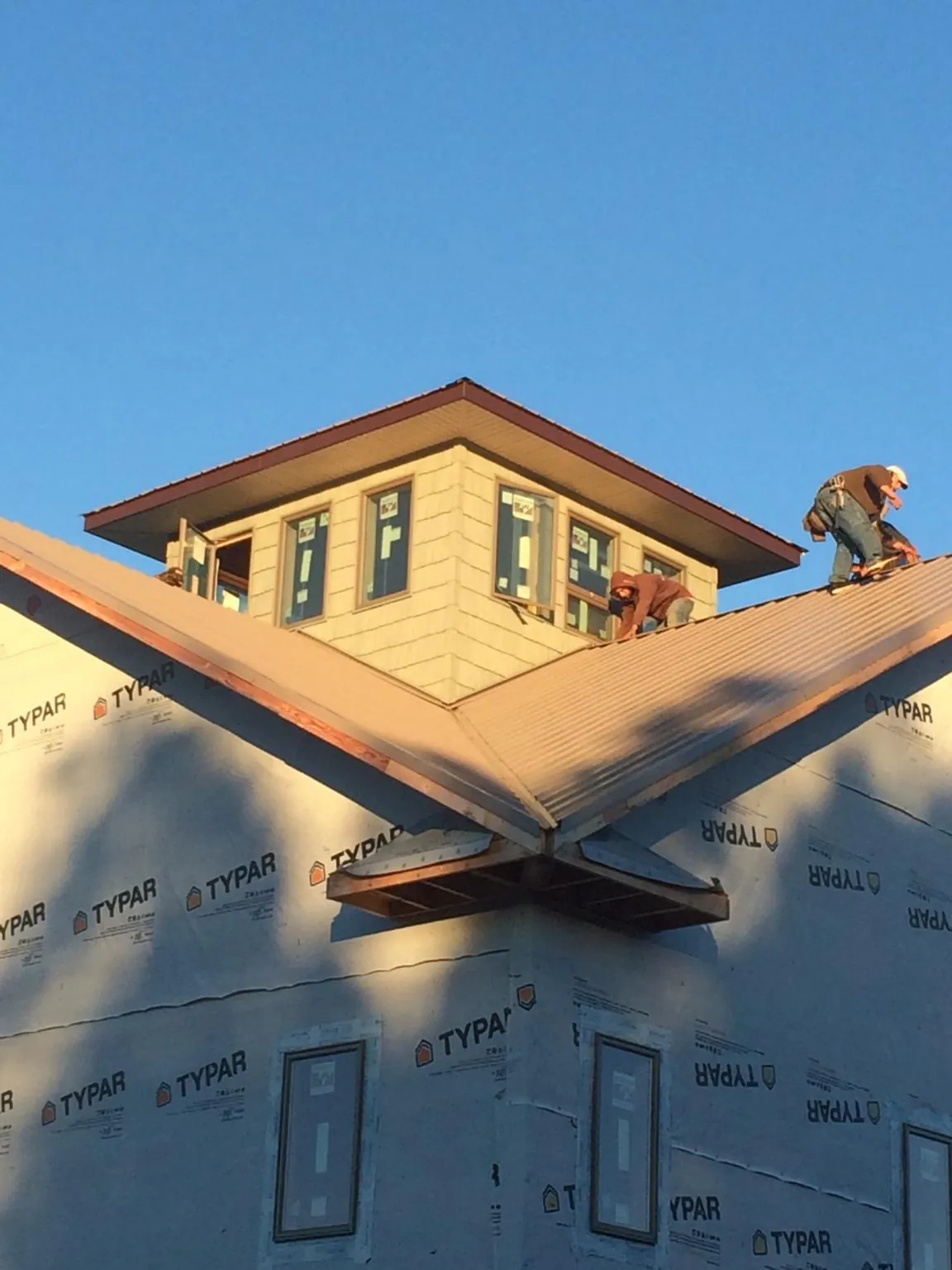 Roofers working around a rooftop cupola on a new metal roof at sunset — Roof Waterproofing in New Troy by Roofing Brothers